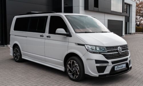 White Volkswagen van parked outside modern building on a clear day.